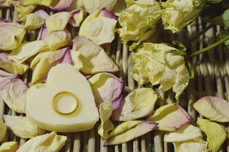 Dried roses and petals with gold ring and candle heart shape (lens blur, soft focus)の写真素材