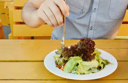 A man eating Green salad with pumpkin oilの写真素材