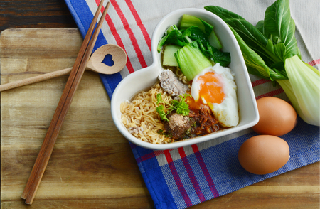 Instant noodle with egg, minced pork, bok choy in heart shape bowl.の写真素材