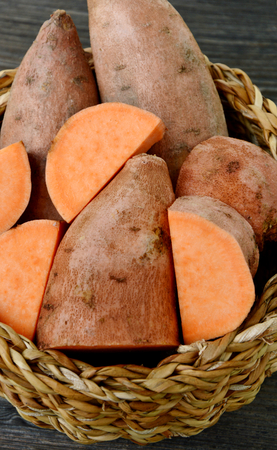 Many sweet potatoes in the basket on wooden backgroundの写真素材
