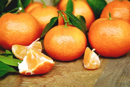 A lot of fresh Mandarins with green leaf on wooden background.の写真素材