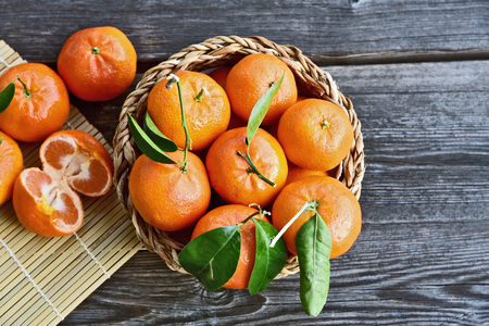 Fresh and Colorful of Mandarin orange and  green leafs with basket and wooden floorの写真素材