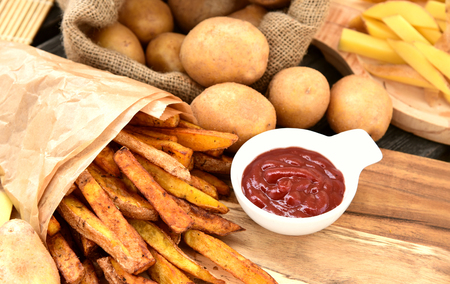 Homemade Crispy Seasoned French Fries.French fries  with spicy seasoning in brown paper bag on...