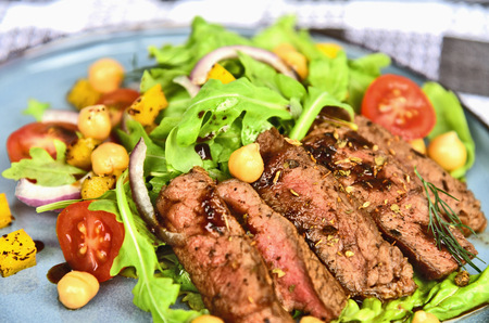 Steak salad with honey soy sauce on blue dish.Beef salad with arugula and chickpeas.の写真素材