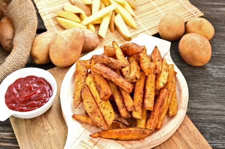 Homemade Crispy Seasoned French Fries.
French fries  with spicy seasoning in wooden plate on wooden broad.の写真素材