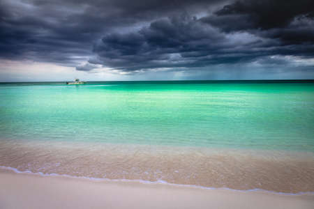 Dramatic sky with storm clouds over caribbean beach with motorboat, Negril Seven Mile Beach, Jamaica