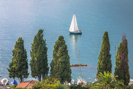 Above idyllic Lake Garda with sailboat in Malcesine at sunset, Italian alpsの写真素材