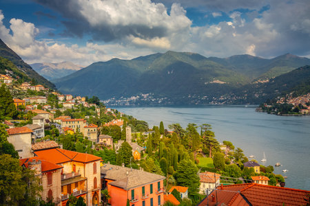 Idyllic Lake Como coastline with village and sailboat at dramatic sunset, Italyの写真素材