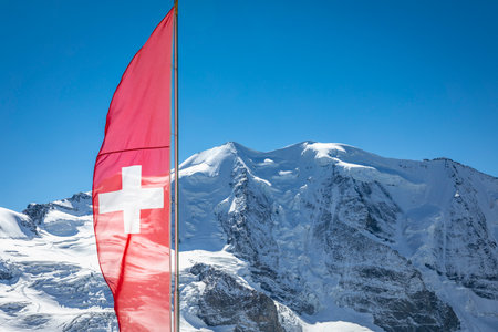 Swiss flag and Bernina mountain range with glaciers in the Alps, Switzerlandの写真素材
