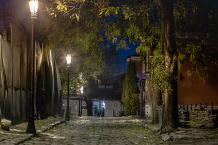 Dark and mysterious alley illuminated by lamps at night in Plovdiv, Bulgariaの写真素材