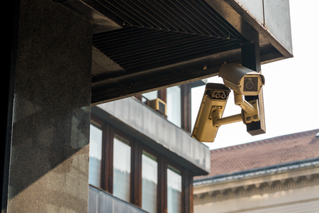 Surveillance video camera is mounted to a brick wall outside a building for security.
