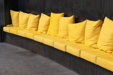 A large long sofa with colored pillows and a metal base in the seating area for guestsの写真素材