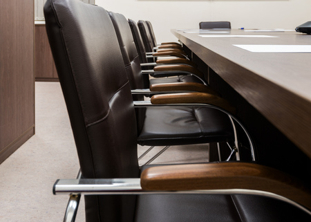 Modern leather chairs with wooden handles in the interior of the conference room near the table