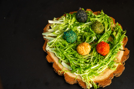 Cheese balls on a wooden plate with greens on a black backgroundの写真素材