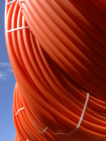 plastic pipes stacked in rolls on the street on the sky backgroundの写真素材