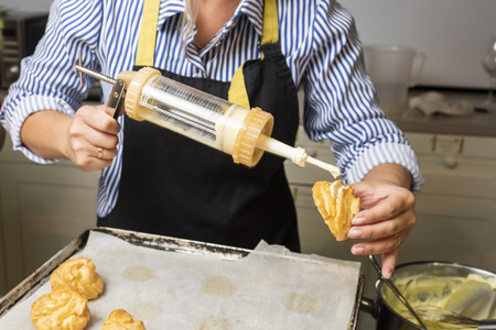 filling the eclairs with a confectionery syringe with female hands