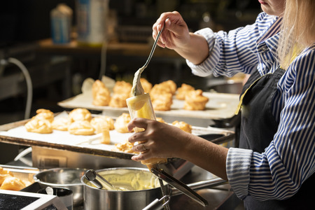 ready-made butter cream for cakes in a spoon that fills the pastry gun in female handsの写真素材