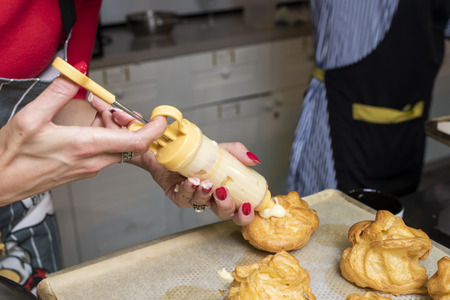 filling the eclairs with a confectionery syringe with female handsの写真素材