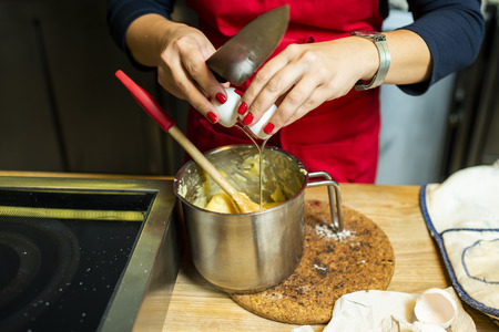 adding eggs to dough for buns, making dough with yolkの写真素材