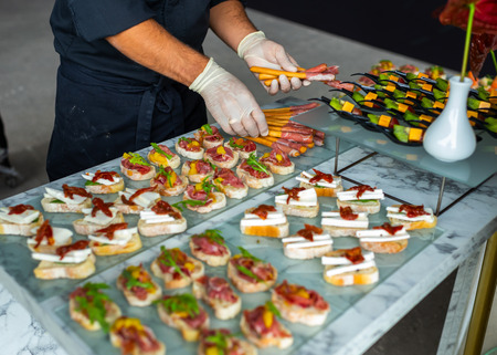 men's hands in gloves lay out a treat for guests at the banquetの写真素材