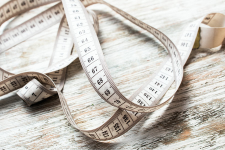 centimeter for tailors and sports for measuring the waist and clothes on a wooden background