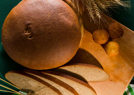 loaf of bread with sliced bread on a table with spikelets, top viewの写真素材
