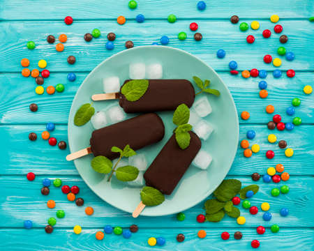 chocolate ice cream and candies on a plate, on a blue wooden table, top viewの写真素材