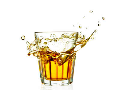 whiskey in a glass splash isolated on white background with reflectionの写真素材