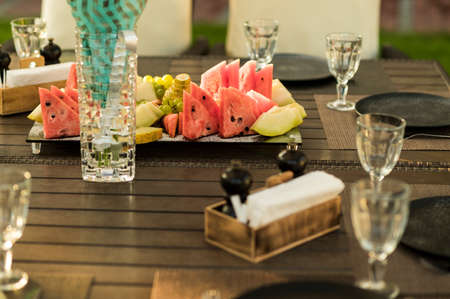 served table with fruit slices on a plate and glassesの写真素材