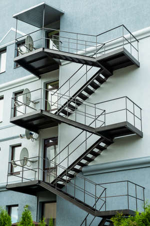 black fire escape on a building with satellite dishes installedの写真素材