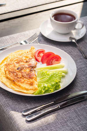 breakfast of scrambled eggs with tomatoes and cucumbers and teaの写真素材