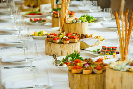 CanapÃ©s on the plates with cold appetizers and cheese sliced on a serving tableの写真素材