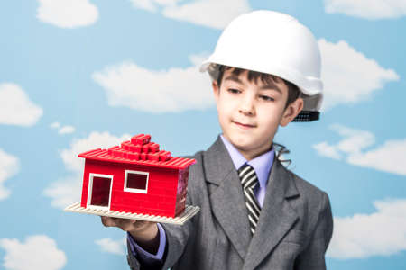 boy in jacket holding a pencil in his mouth and thinks holding a cookie sheet of paperの写真素材