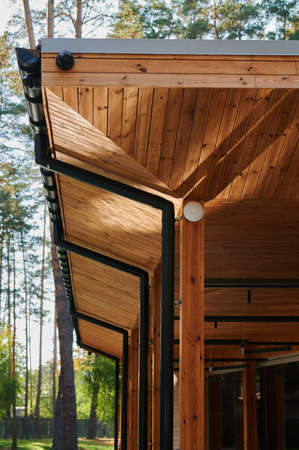 The roof of an open veranda made of wood trim with plastic pipes for rain gutters, an element of architectureの写真素材