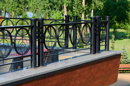 modern black painted metal fence in an urban environment on a sunny dayの写真素材