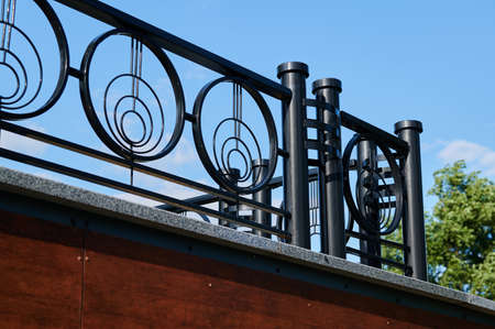 Street black metal fence in an urban environment on a sunny day against the skyの写真素材