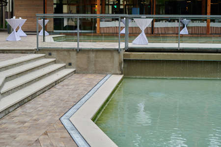 Walkway and ceramic tile with stone and metal gutter with grating around outdoor water pool outdoorsの写真素材