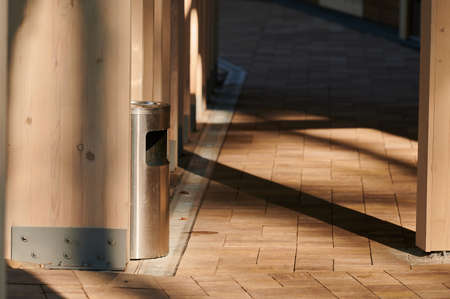 a metal trash can near a wooden gazebo among landscaping, building element in the rays of the setting sunの写真素材