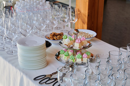 meringue cakes on a two-tiered tray with dishes on a table at a party for receiving guests at an event in a restaurantの写真素材