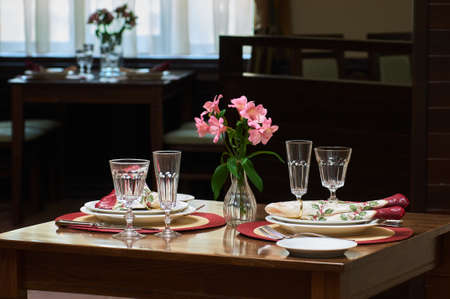table setting with dishes and flowers, a table in a cafe served for the arrival of guestsの写真素材