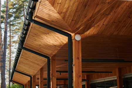 The roof of an open veranda made of wood trim with plastic pipes for rain gutters, an element of architectureの写真素材