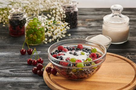 Preservation in jars with berries on a wooden table, a mix of blueberries, gooseberries, raspberries, black currantsの写真素材