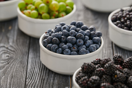 Ripe blueberries on the table in a plate, among the assortment of ripe berries, raspberries, blueberries, gooseberries, currants, shot close-upの写真素材