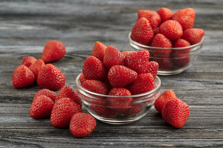 ripe juicy strawberries in two glass bowls, juicy red berries on the tableの写真素材