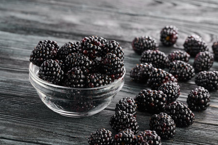 Ripe blackberries in glass saucers on a dark table background, close-up shotの写真素材