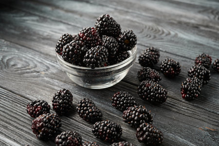 Ripe blackberries in bowls on a wooden table, close-up shotの写真素材