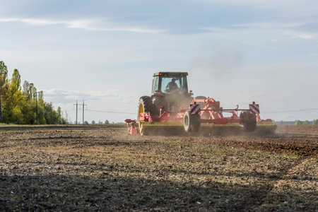 tractor in the field during the sowing season on a sunny day, in a free field in agricultureの写真素材