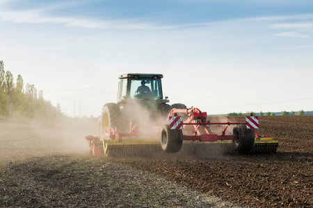 tractor during sowing in an open field on a sunny dayの写真素材