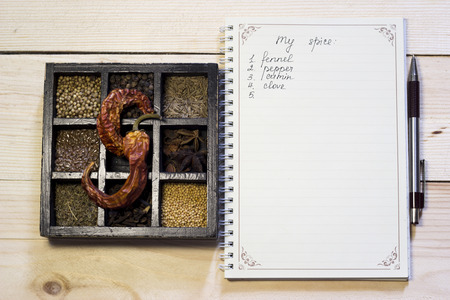 Set of spices in dark wooden case near the notebook and pen to list ingredientsの写真素材