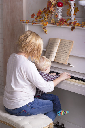 Mom teaches a little child to play the pianoの写真素材